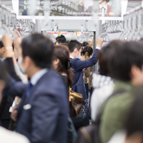 Passengers traveling by Tokyo metro. Business people commuting to work by public transport in rush hour. Shallow depth of field photo. Horizontal composition.